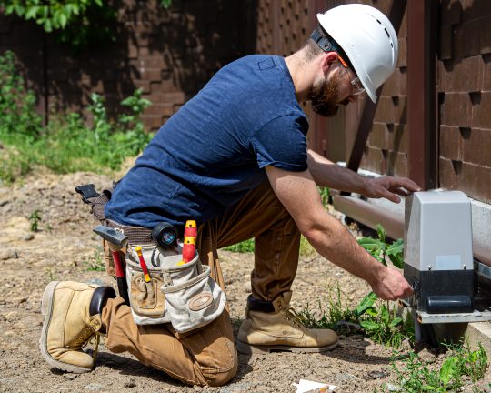 Electrician Builder at work, servicing the fuselage industrial switchboard. Professional in overalls with an electrician's tool.